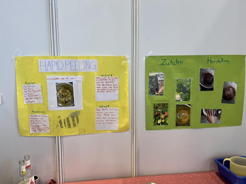 Zwei Plakate an einer Wand, eines in Gelb und eines in Grün, mit Informationen zu Handpeeling und Zutaten.