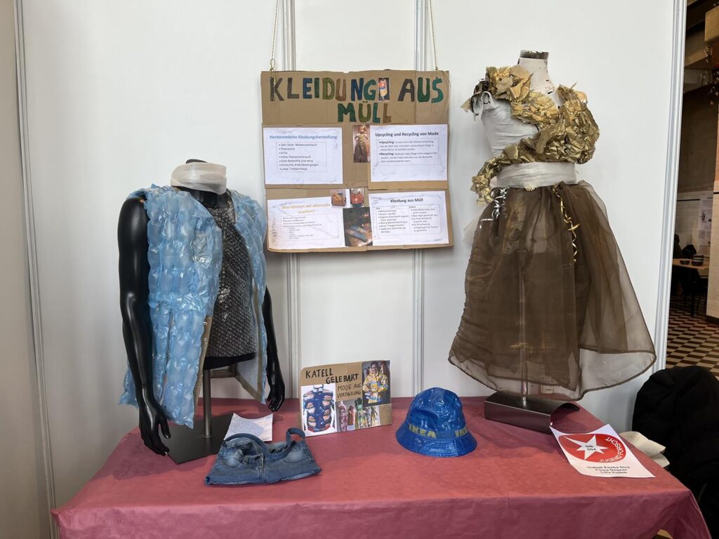 Ausstellung mit Kleidungsstücken aus Müll und Informationen dazu.