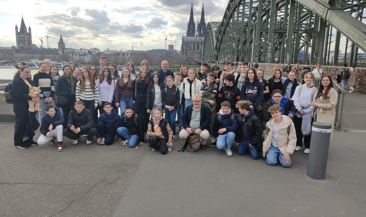 Gruppe von Schülern auf einer Brücke mit Stadtansicht im Hintergrund.