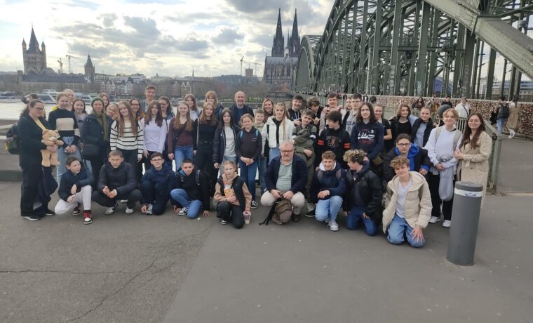 Gruppe von Schülern auf einer Brücke mit Stadtansicht im Hintergrund.
