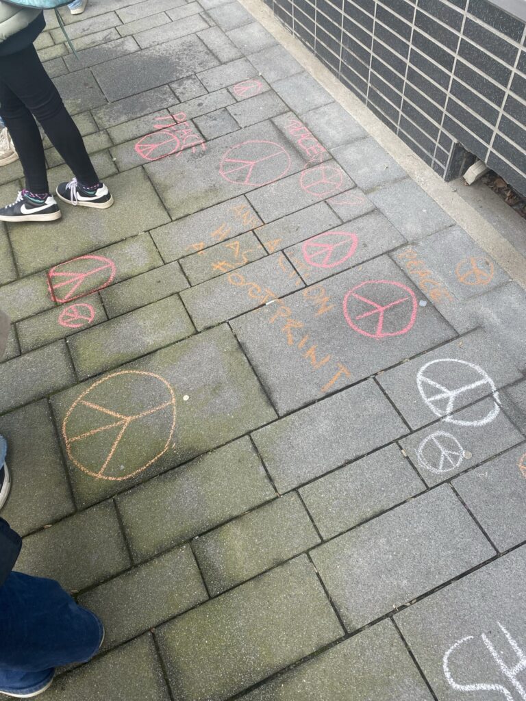 Friedenssymbole aus Kreide auf einem Gehweg.