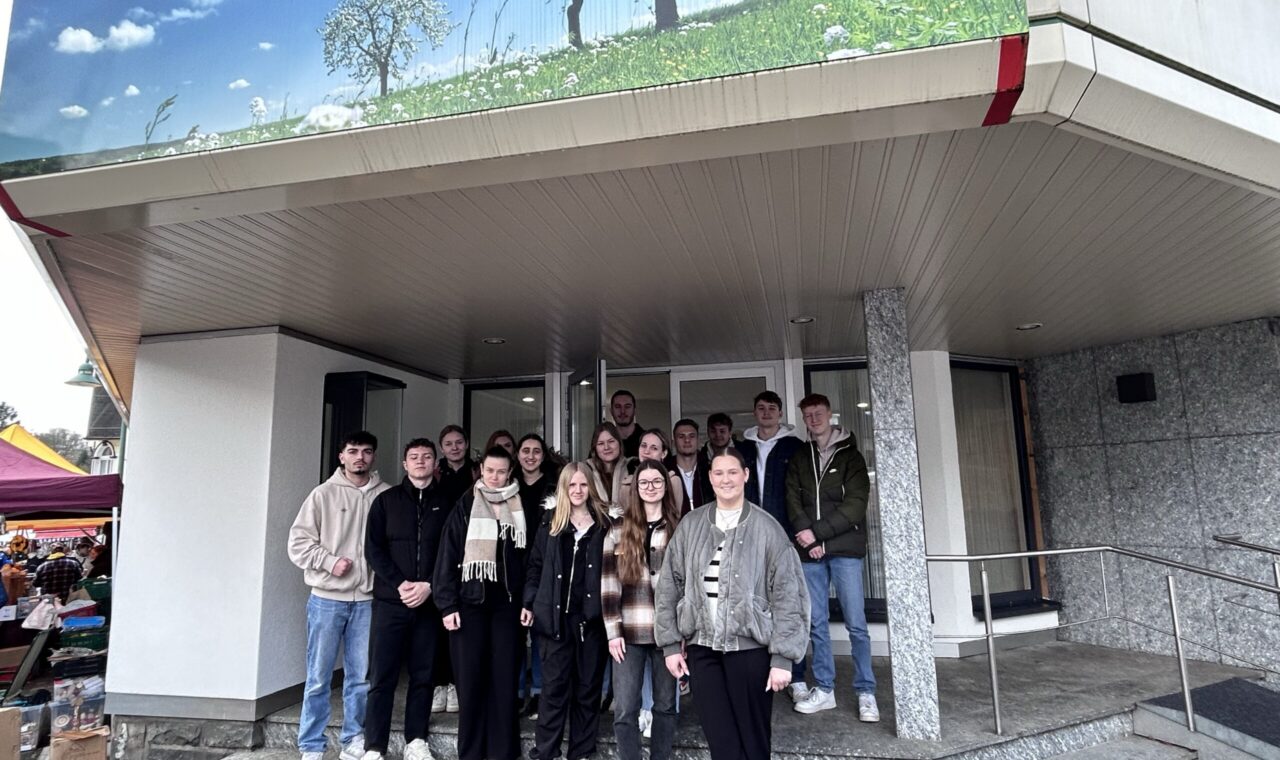 Gruppe von Schülerinnen und Schülern vor einem Gebäudeeingang.