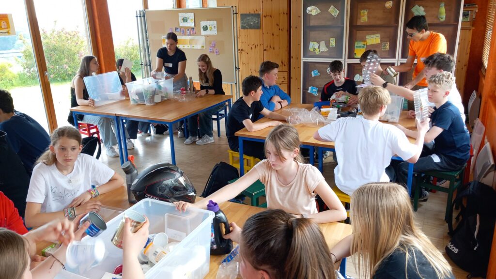 Schülerinnen und Schüler arbeiten an Tischen in einem Klassenraum.