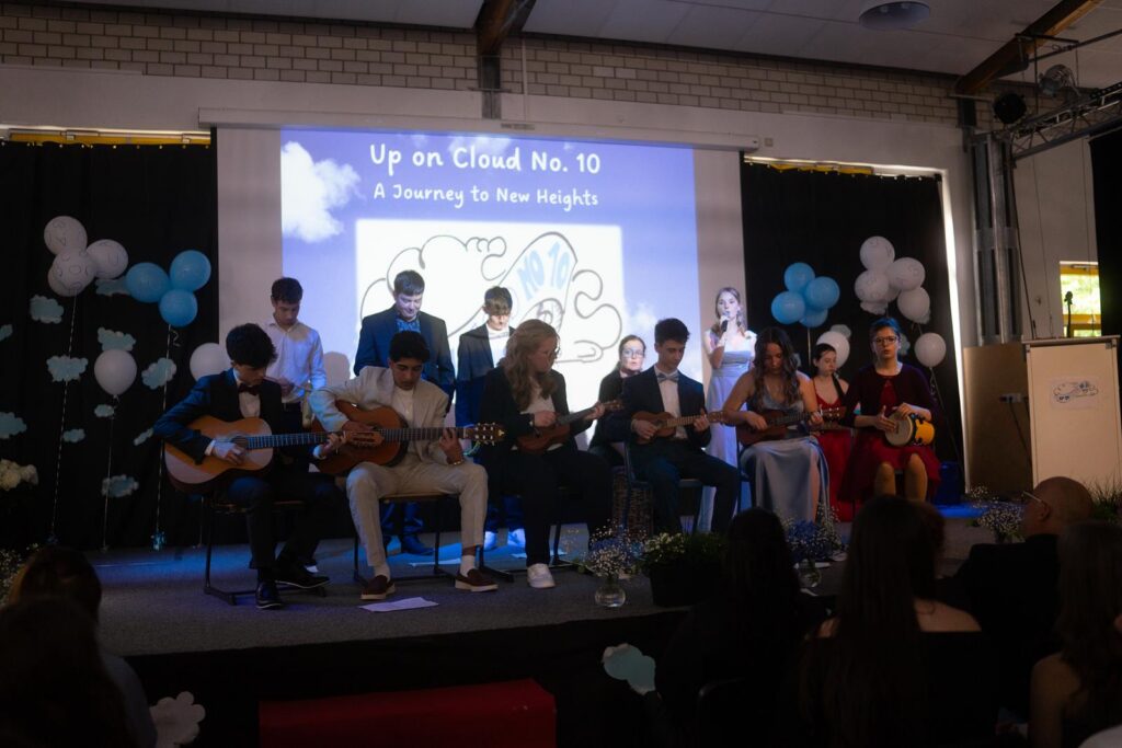 Schüler spielen auf der Bühne Gitarre und singen bei einer Veranstaltung.