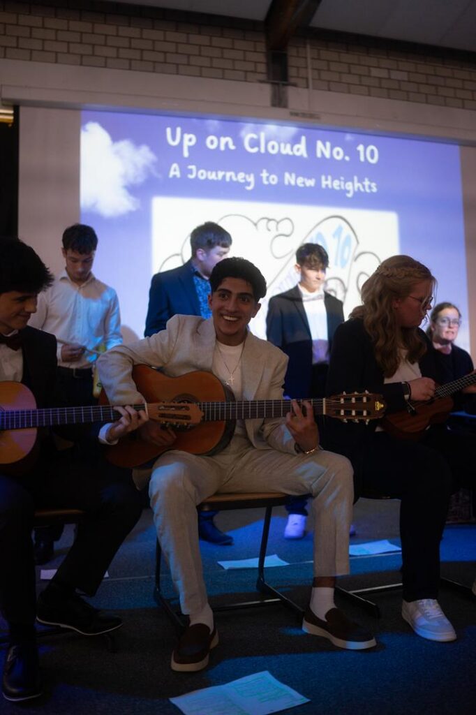Schüler spielen Gitarre während einer Aufführung vor einer Leinwand.