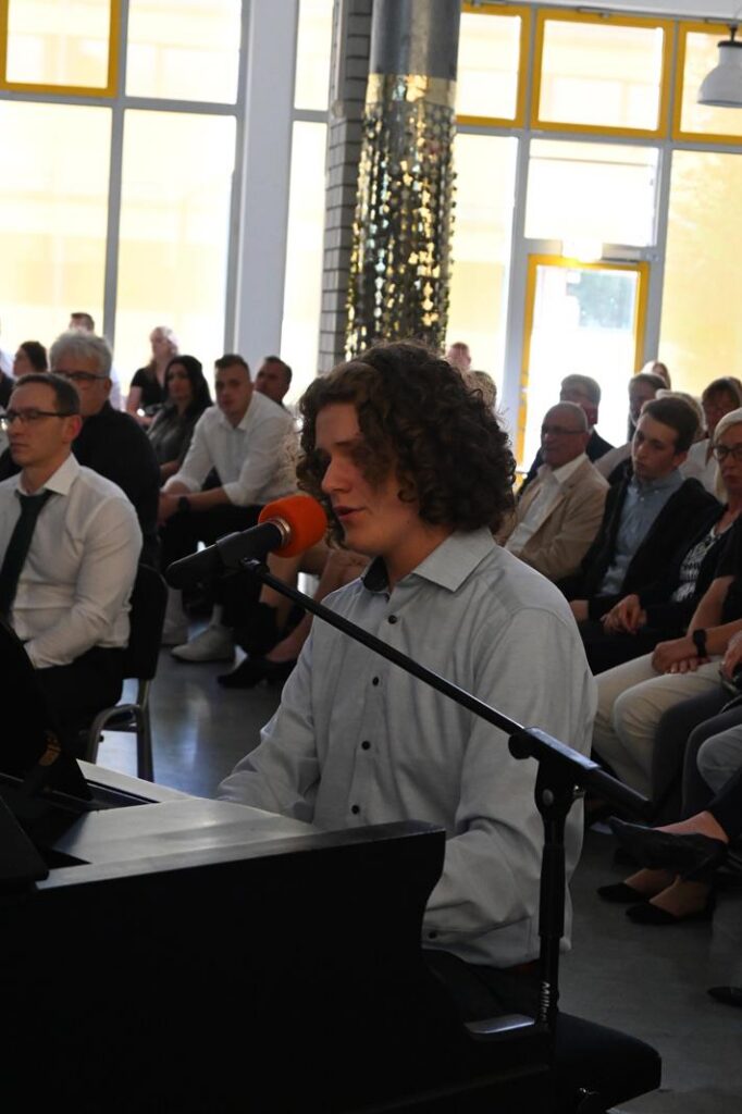 Ein junger Mann spielt Klavier und singt vor einem Publikum.