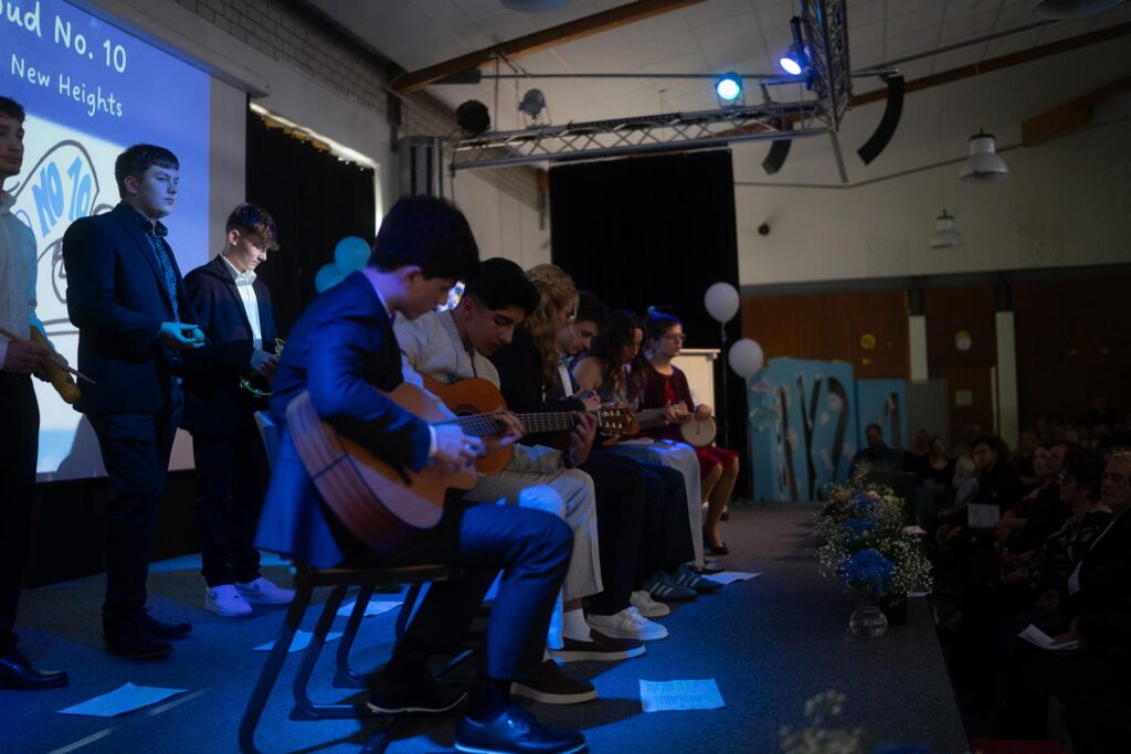 Schüler spielen Gitarre auf einer Bühne bei einer Schulveranstaltung.