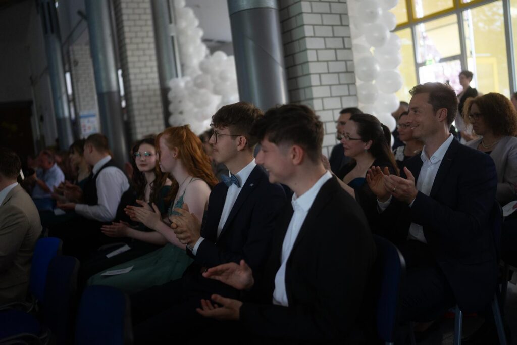 Menschen sitzen in einem Saal und applaudieren.