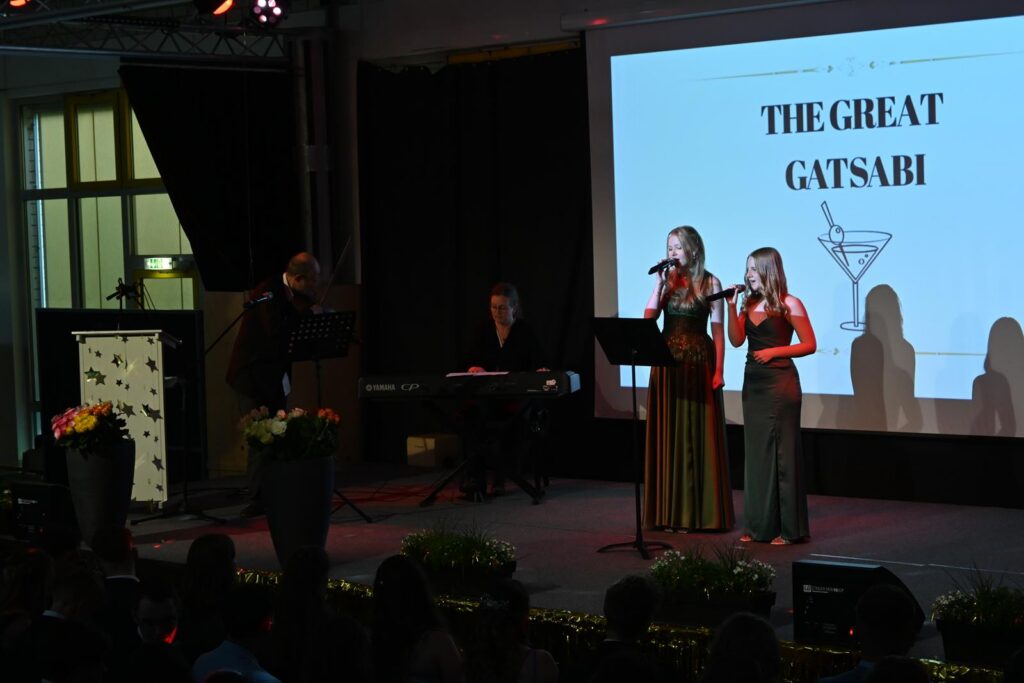 Zwei Sängerinnen performen auf einer Bühne vor einem Publikum.