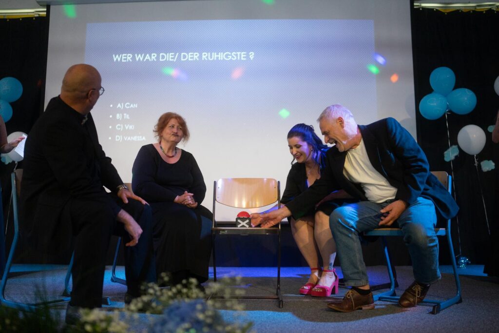 Podiumsdiskussion mit vier Personen, während eine Frage auf einer Leinwand angezeigt wird.