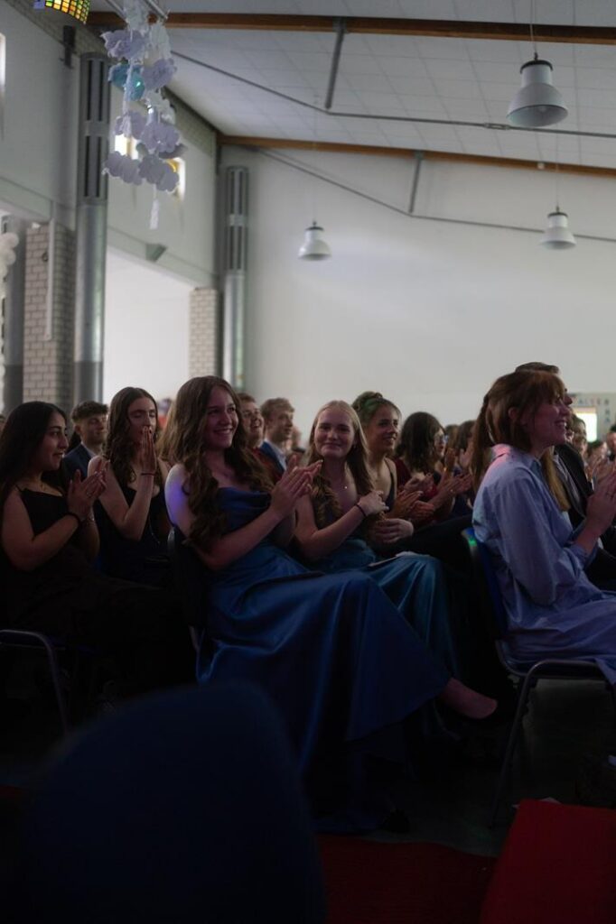 Gruppen von Menschen applaudieren in einem festlichen Saal.
