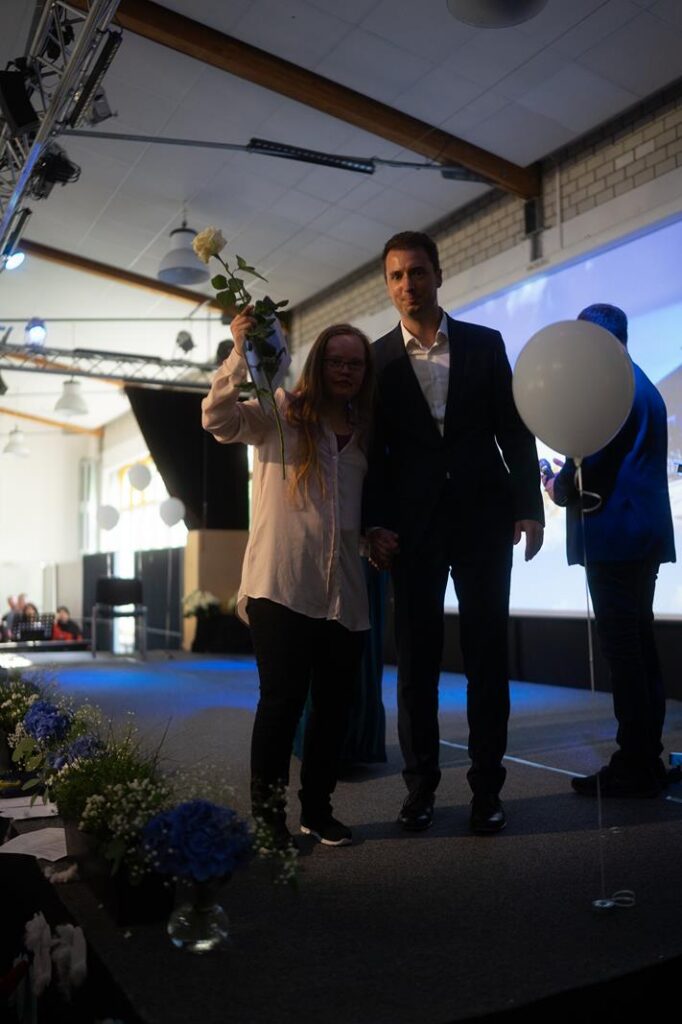 Eine Person überreicht einen Blumenstrauß auf einer Bühne.
