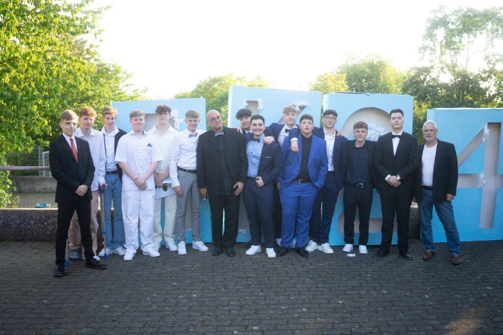 Gruppe von Jugendlichen in formeller Kleidung vor blauen Zahlen.