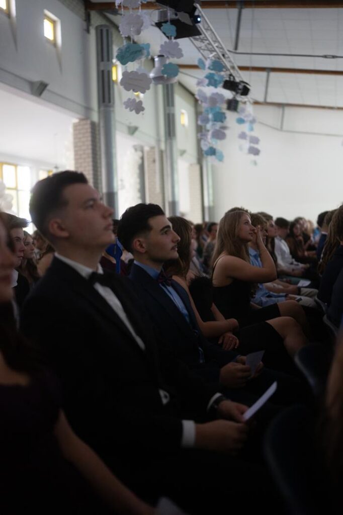 Schüler sitzen aufmerksam in einem festlichen Saal während einer Veranstaltung.