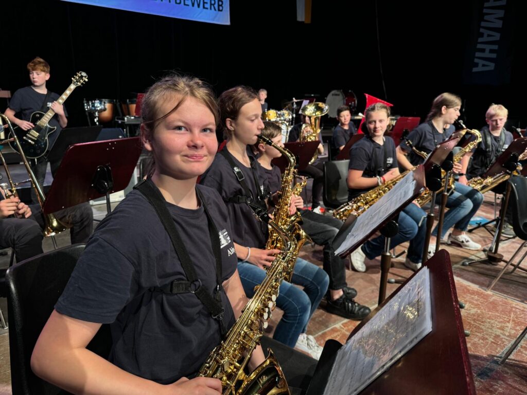 Schüler spielen Saxophon in einer Schulband auf der Bühne.