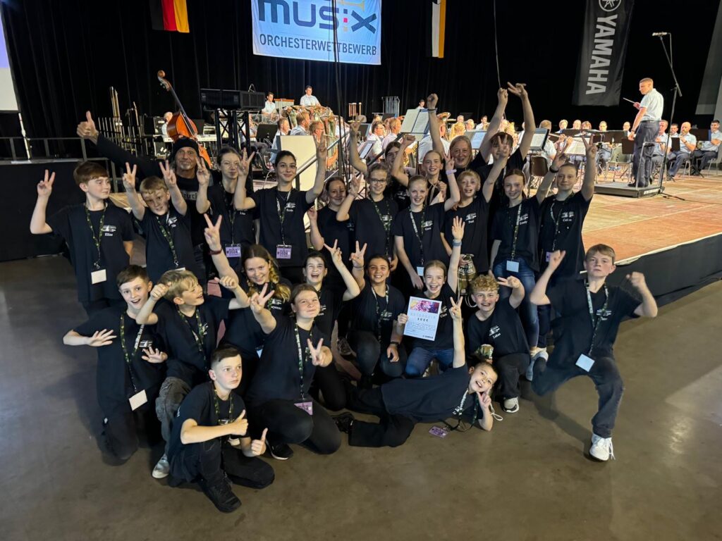 Gruppenshooting von Schülern in schwarz gekleideten T-Shirts bei einem Musik-Event.