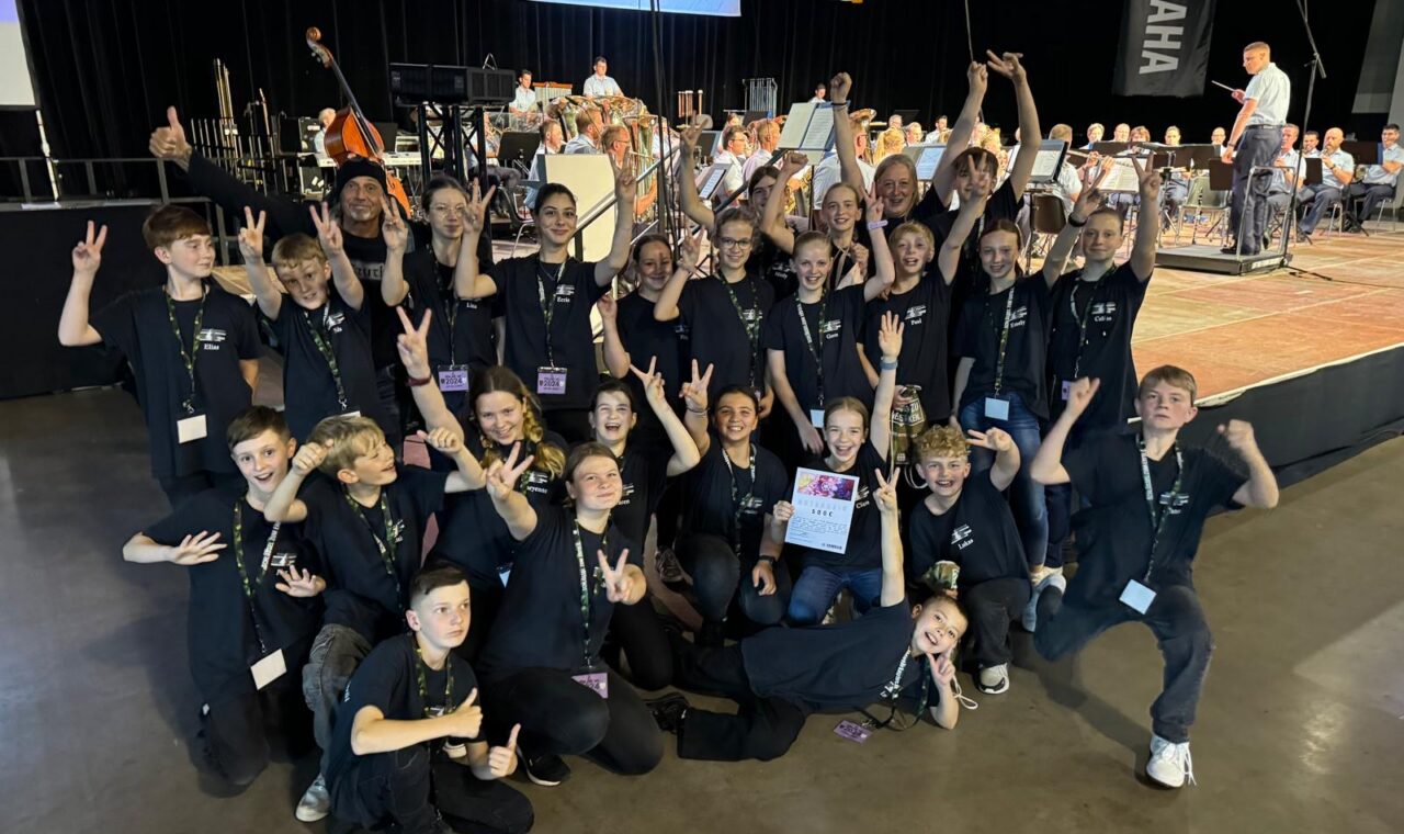 Gruppenshooting von Schülern in schwarz gekleideten T-Shirts bei einem Musik-Event.