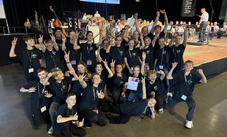 Gruppenshooting von Schülern in schwarz gekleideten T-Shirts bei einem Musik-Event.