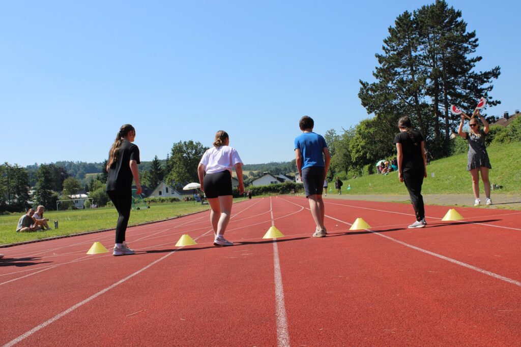 Vier Schüler stehen auf der Laufbahn, bereit zum Wettlauf.