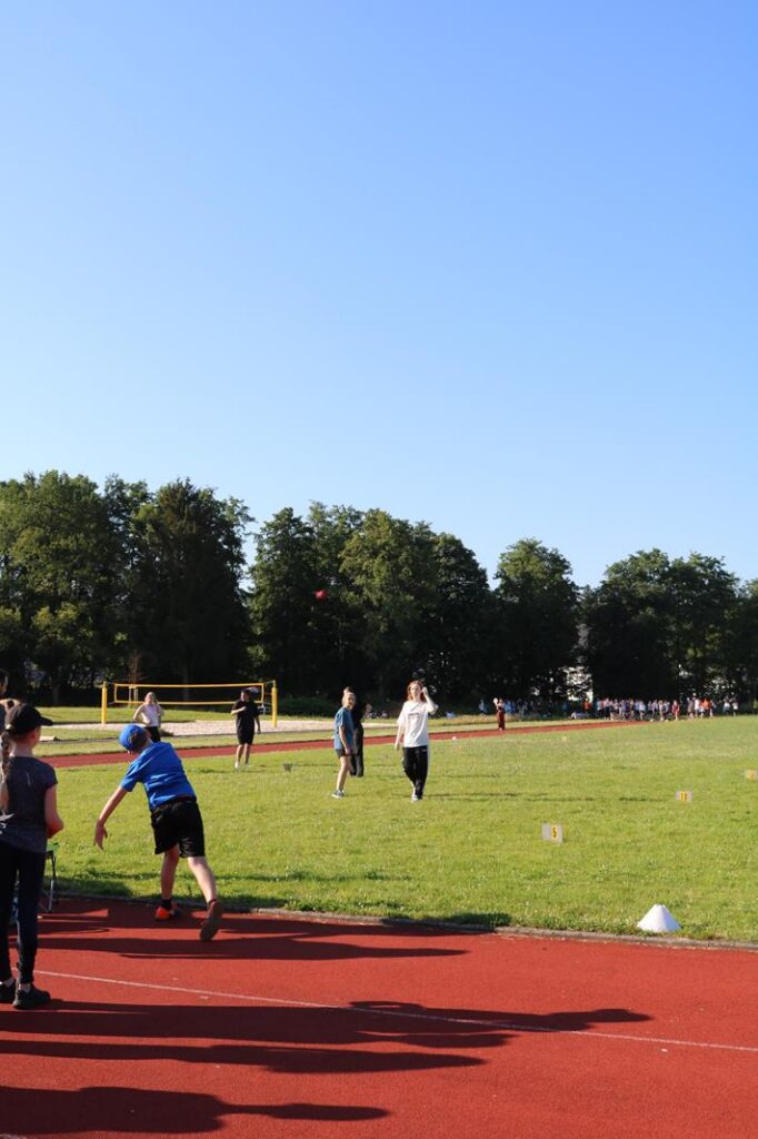 Schüler beim Sport auf einem offenen Feld mit blauen Himmel.