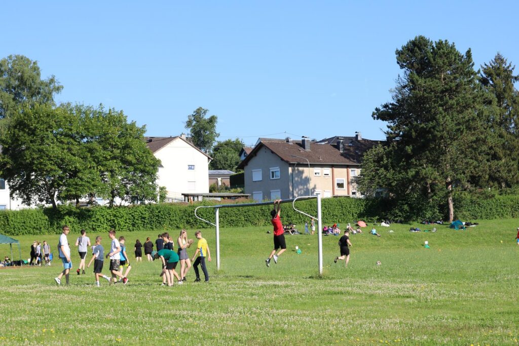 Schüler spielen Fußball auf einem Feld bei sonnigem Wetter.