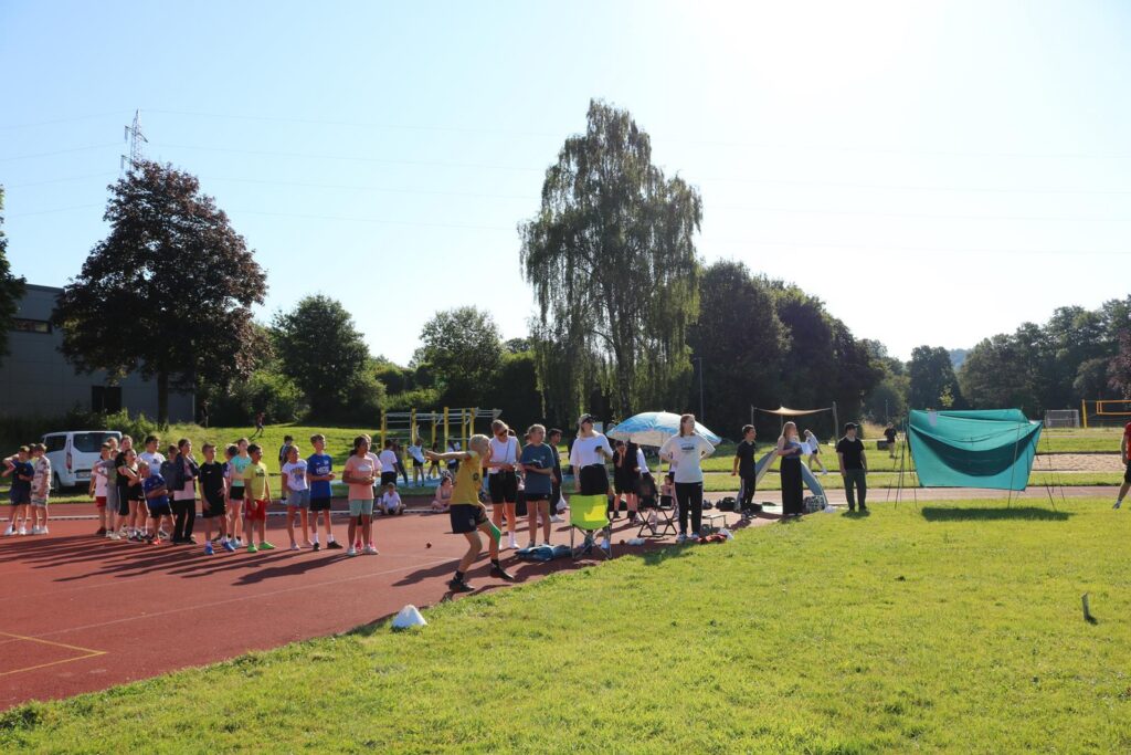 Schülerinnen und Schüler bei Sportaktivitäten auf einem Platz im Freien.