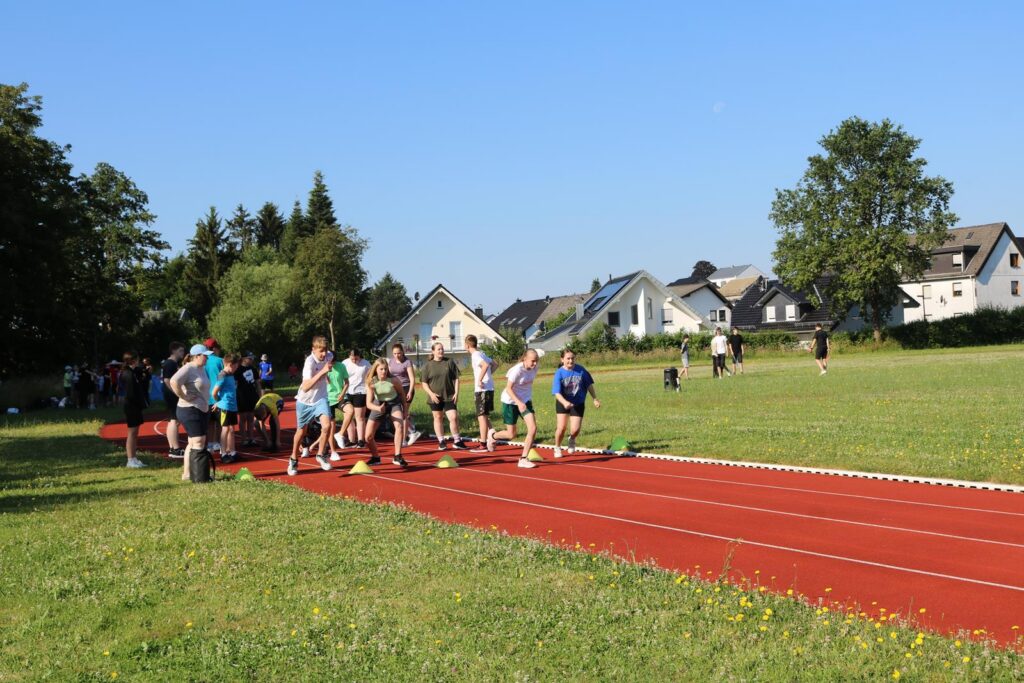 Athleten starten auf einer roten Laufbahn bei einem Wettkampf im Freien.