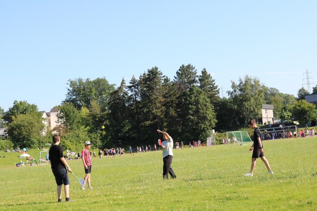 Schüler spielen im Freien auf einem großen grünen Feld.