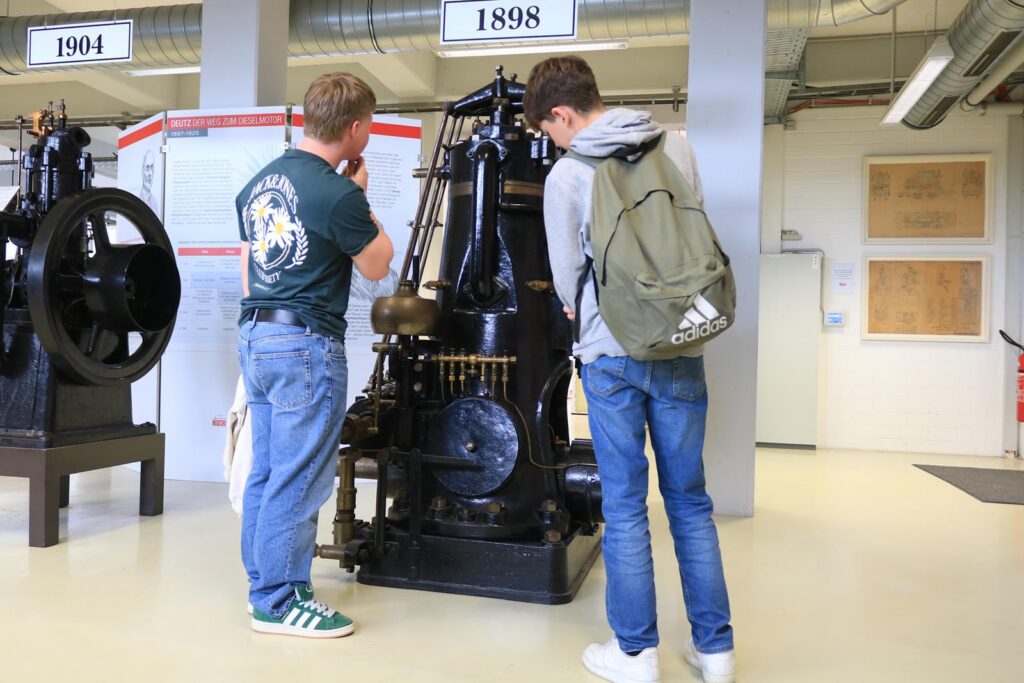 Zwei Schüler betrachten eine historische Maschine im Technikmuseum.