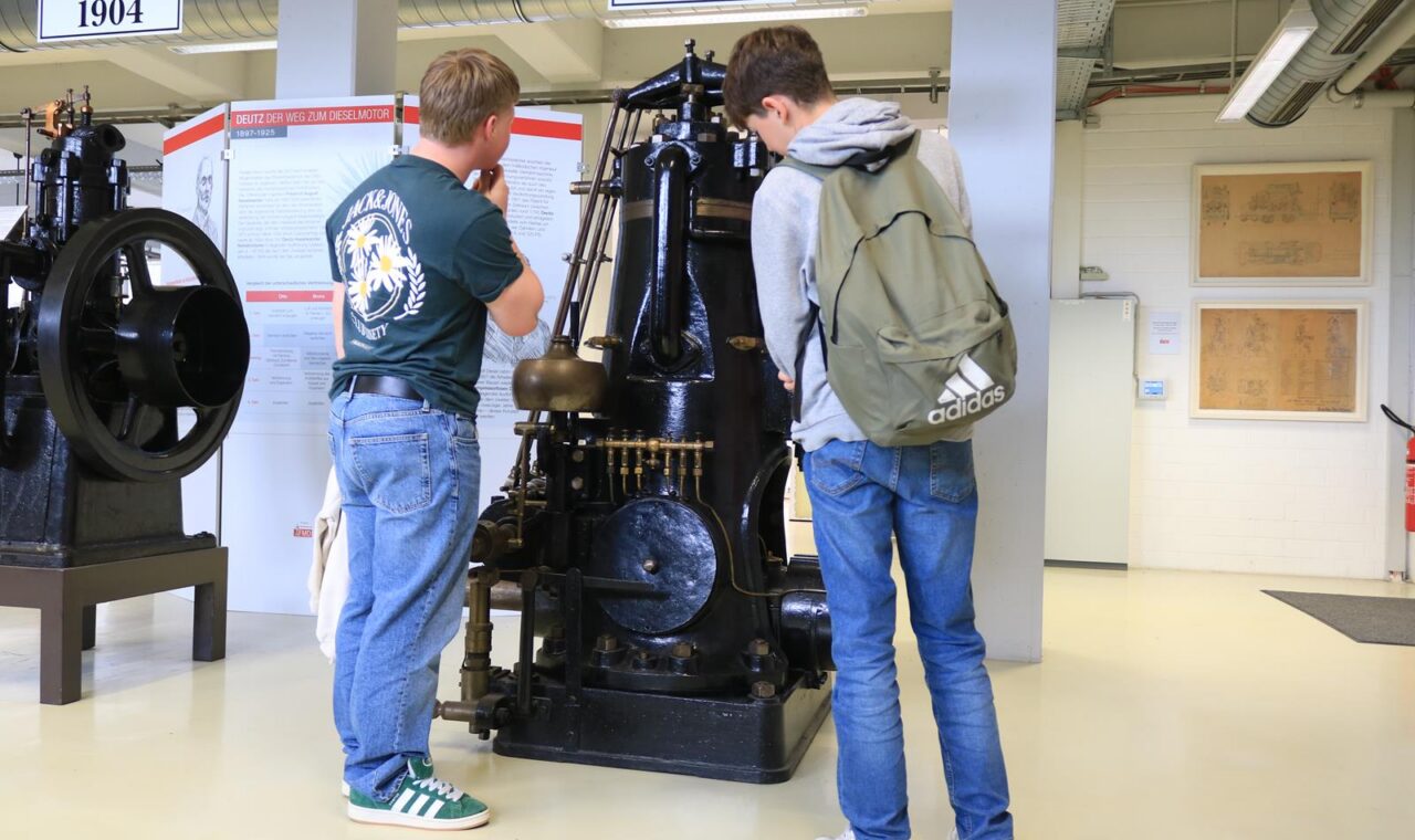 Zwei Schüler betrachten eine historische Maschine im Technikmuseum.