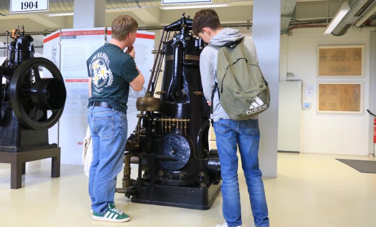 Zwei Schüler betrachten eine historische Maschine im Technikmuseum.