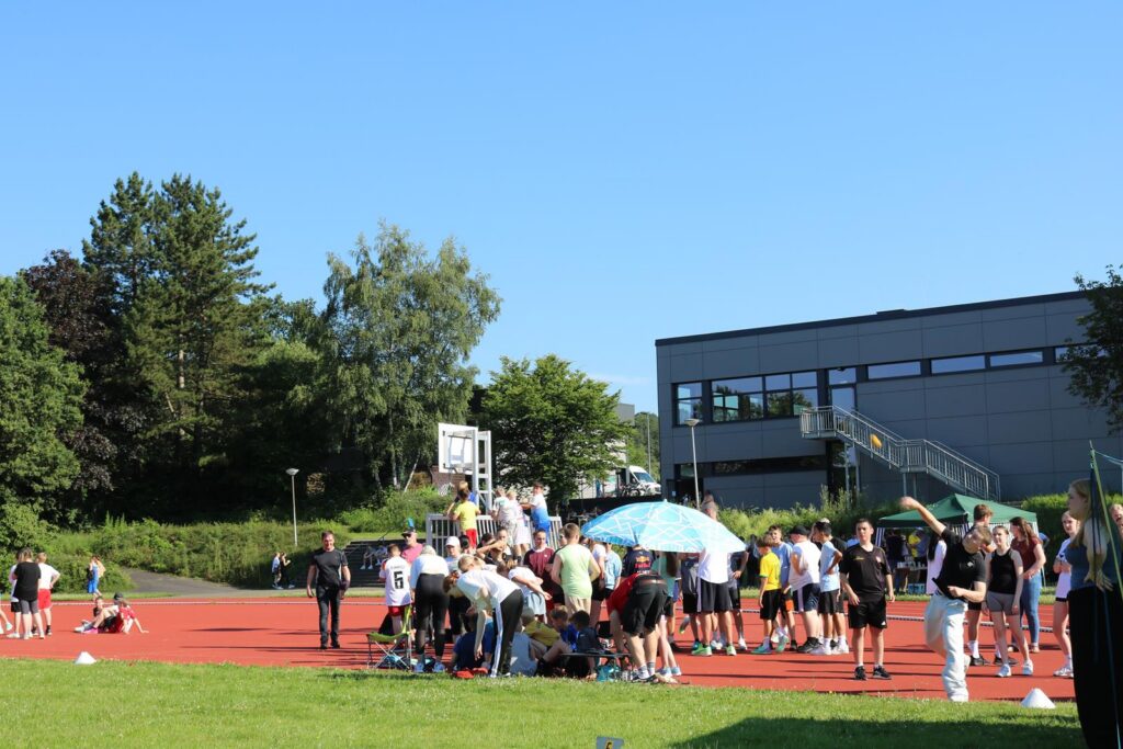 Menschen auf einem Sportplatz versammeln sich bei schönem Wetter.