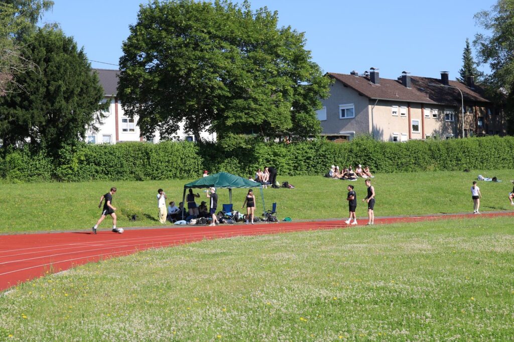 Sportveranstaltung auf einer Laufbahn mit Teilnehmern und Zuschauern im Hintergrund.
