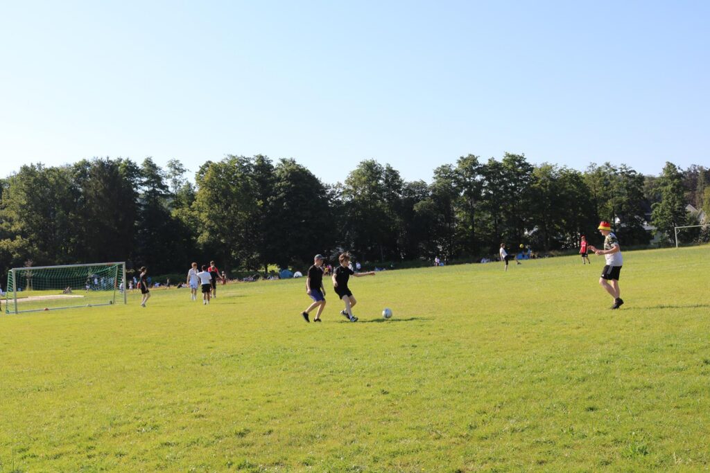 Fußballspiel auf einem grünen Platz unter blauem Himmel.