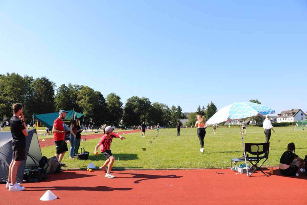 Sportveranstaltung auf einem Rasenplatz mit Athleten und Zuschauern.
