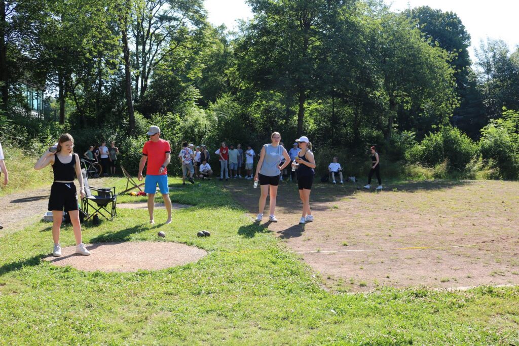 Sportveranstaltung im Freien mit Teilnehmern und Zuschauern auf einer Wiese.