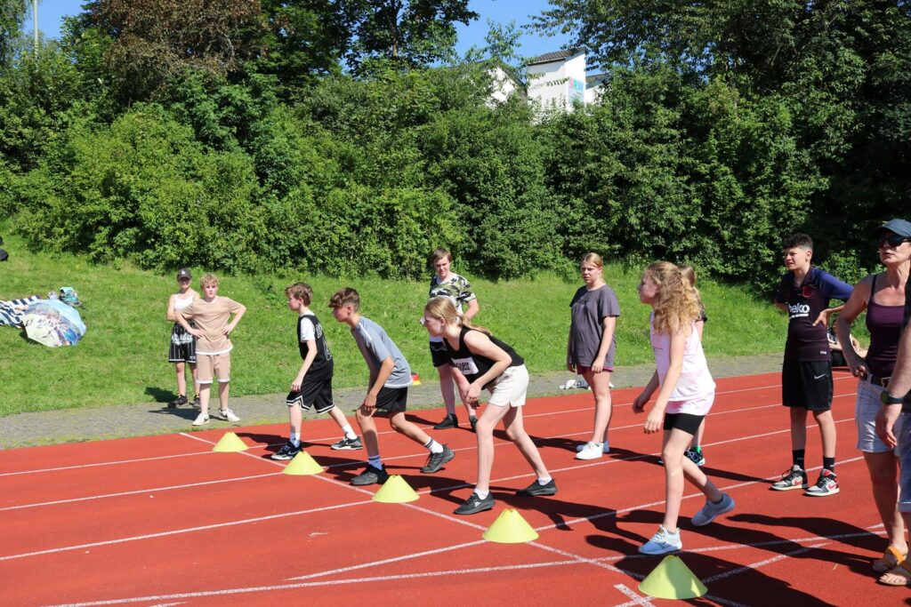 Sportlerinnen und Sportler stehen an der Startlinie eines Laufwettbewerbs.