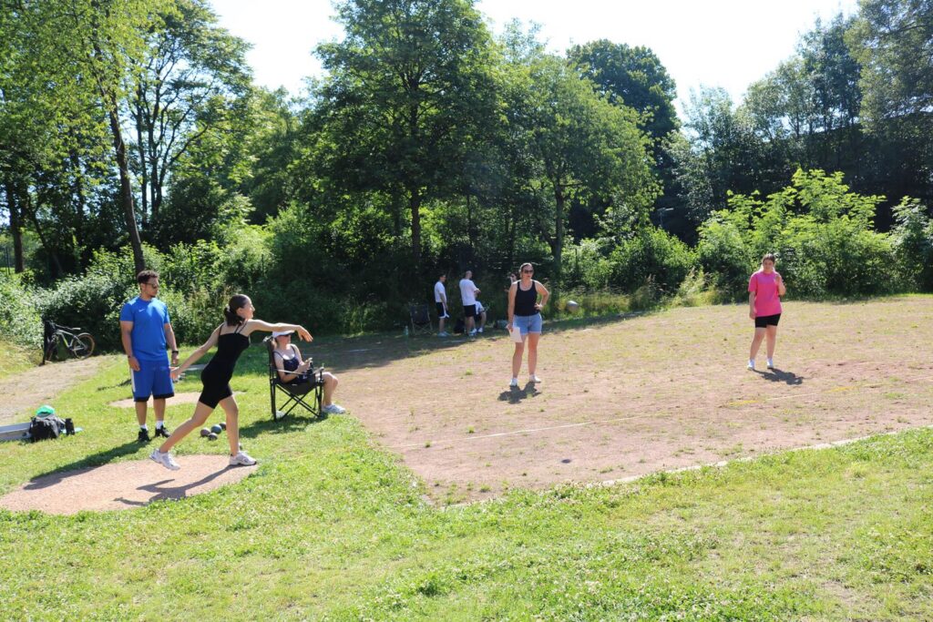 Schüler*innen beim Sport im Freien auf einem Rasenplatz.