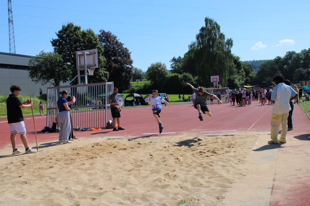Schüler beim Weitsprungwettbewerb auf einem Sportplatz.