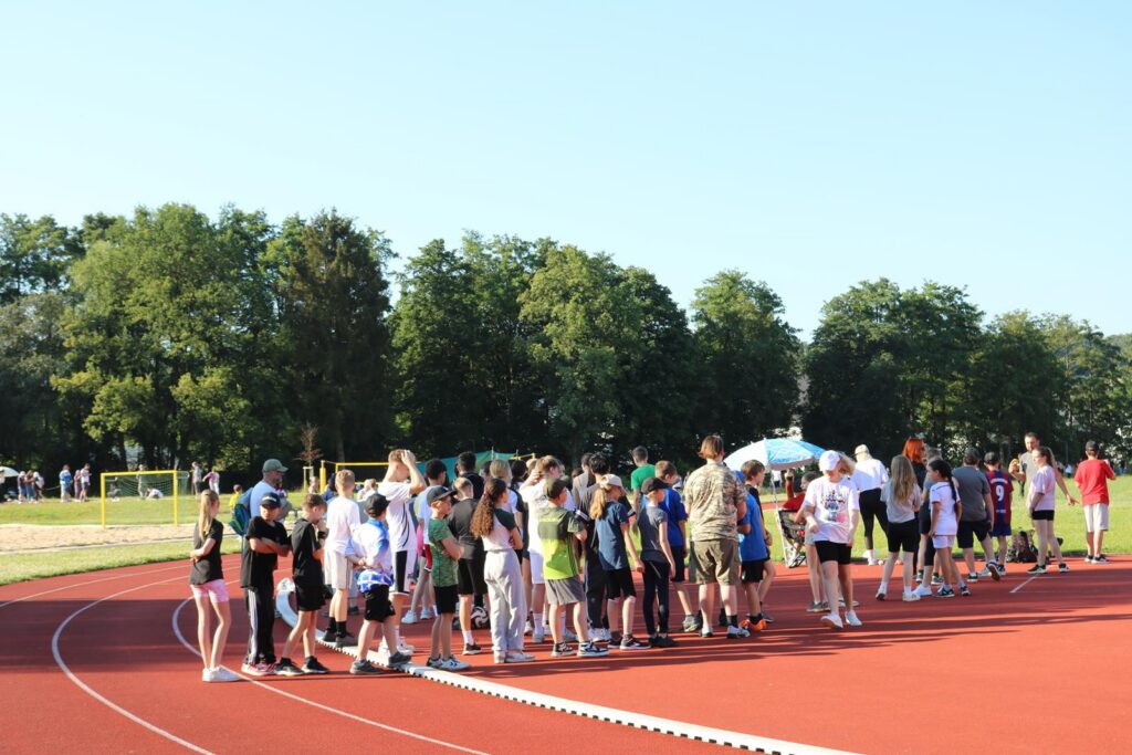 Gruppe von Kindern und Erwachsenen auf einem Sportplatz, bereit für einen Wettkampf.