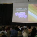 Die Bühne mit Projektor und Publikum bei einer Präsentation der Musikklasse 6d.