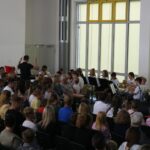 Schülermusiker spielen vor einem Publikum in einem festlich dekorierten Raum.