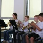 Schüler spielen Trompeten in einem Klassenraum.