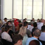 Orchesterprobe mit Musikern und Publikum in einem großen Raum.