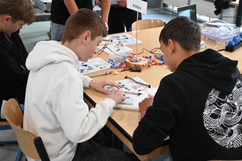 Schüler arbeiten an einem Tisch mit Materialien und Anleitungen.