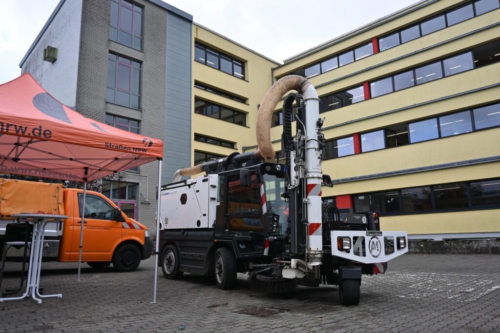 Fahrzeug mit Saugtechnik steht vor einem Schulgebäude.