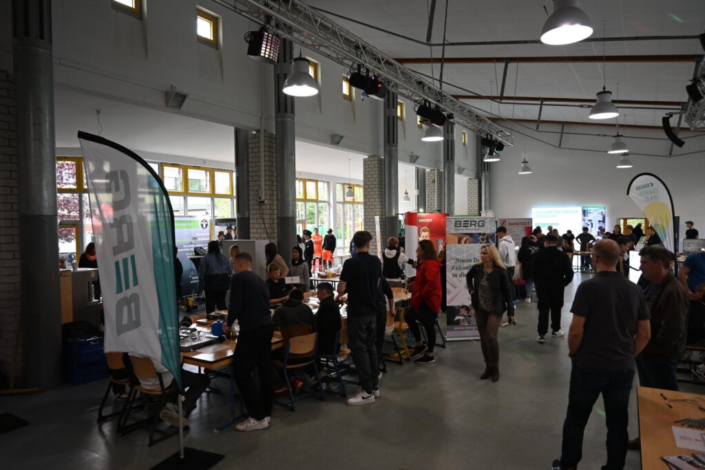 Messe mit Ständen und Besuchern in einem großen Raum.