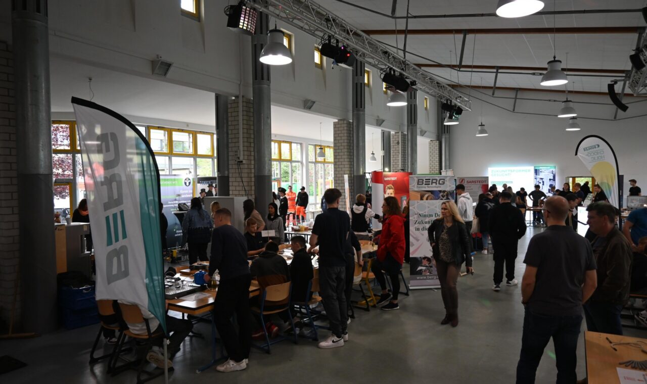 Messe mit Ständen und Besuchern in einem großen Raum.