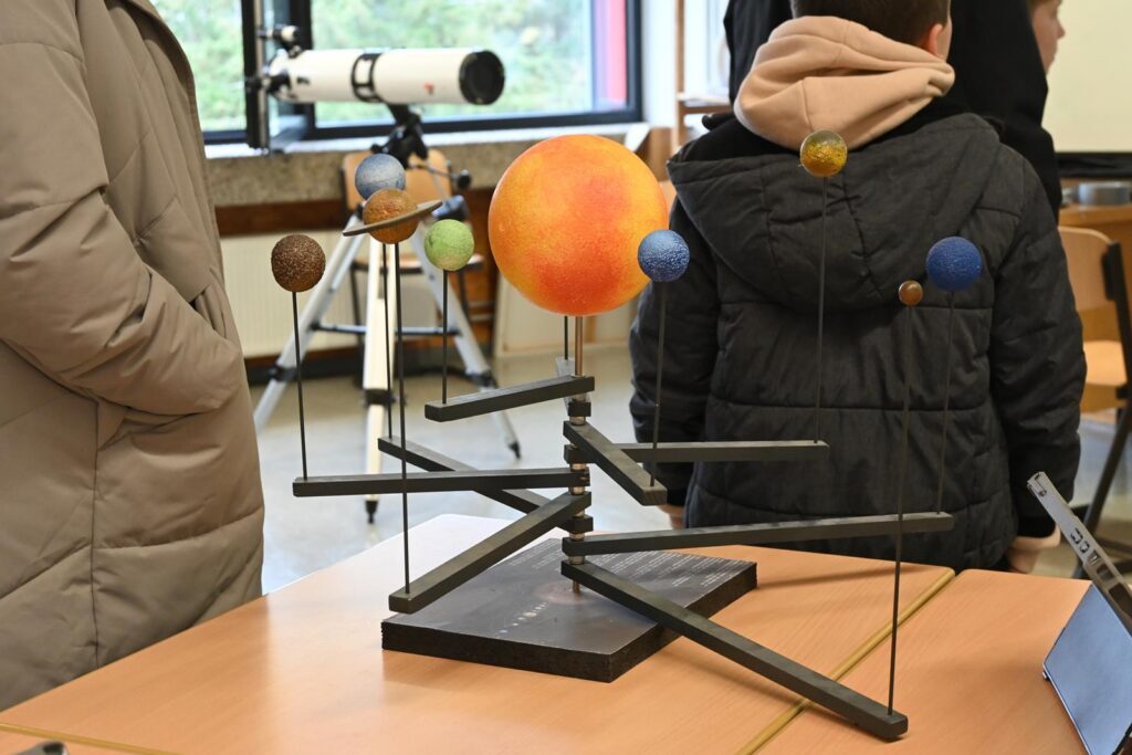 Modell des Sonnensystems mit Planeten und Teleskop im Hintergrund.