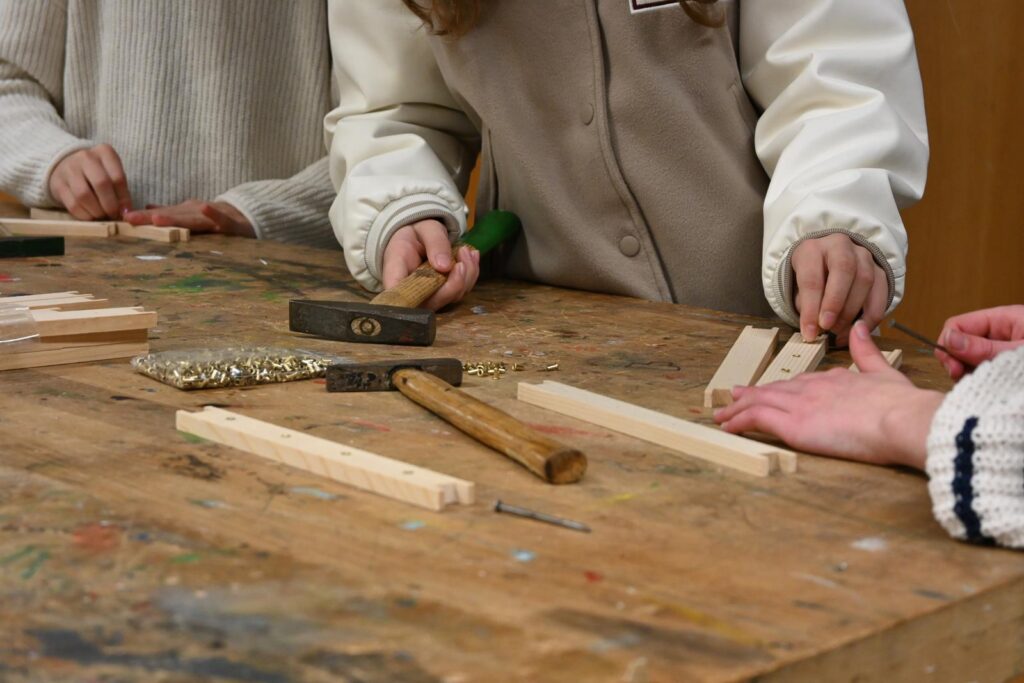 Schüler arbeiten an einem Holzbearbeitungsprojekt am Tisch.